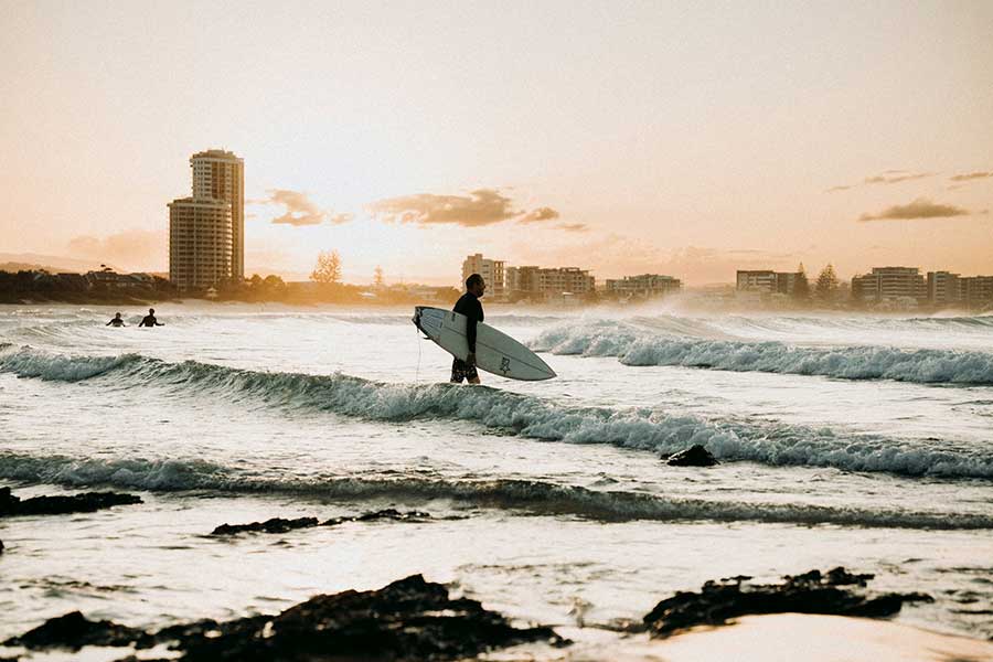 Vagues de surf sur la côte de la Gold Coast avec forêt subtropicale de l'hinterland visible à l'horizon